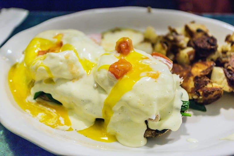 plate of poached eggs with hollandaise sauce and potatoes