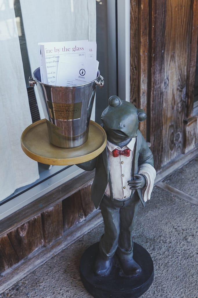 a statue of a frog dressed as a waiter