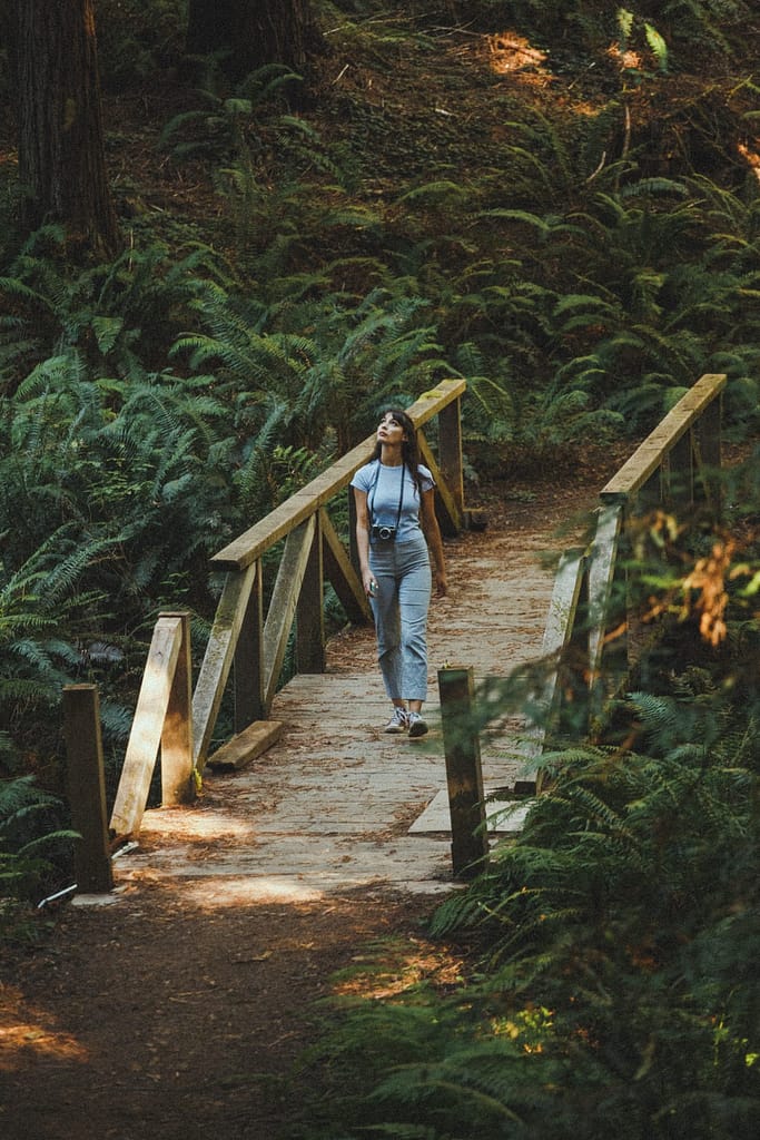 woman walking across a wooden bridge in the woods