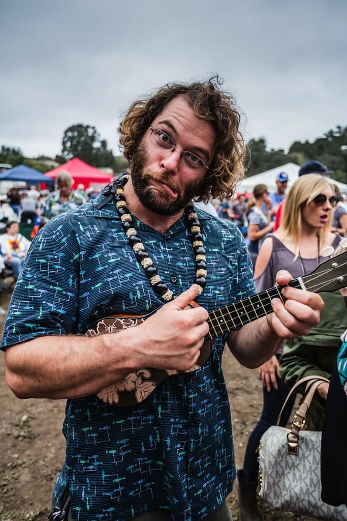 a man making a funny face and playing the ukulele