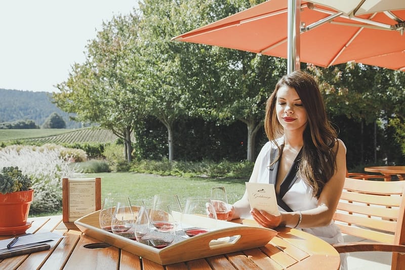 a woman outside at table with glasses of wine