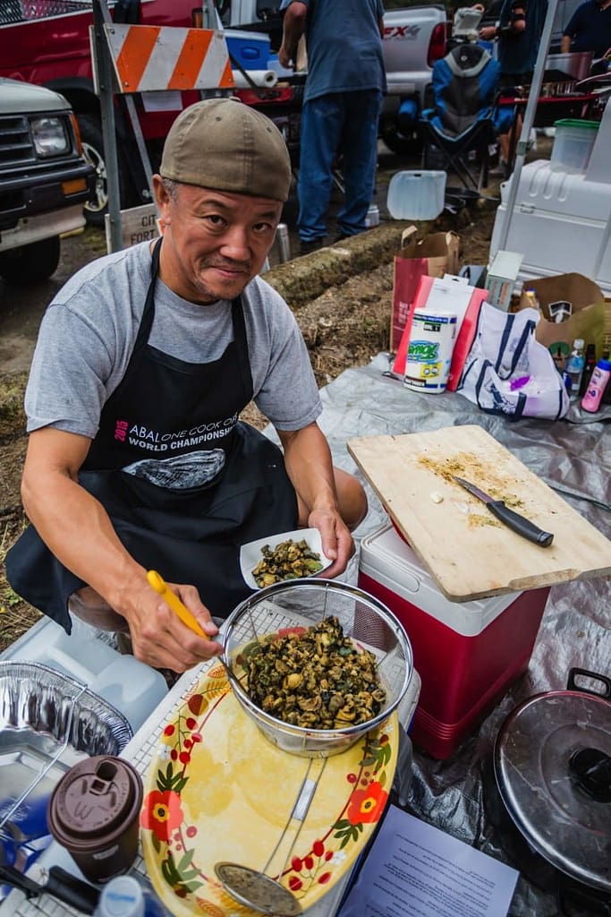a man dishing up pieces of cooked abalone
