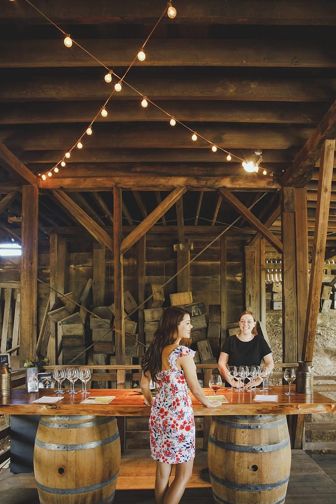 a woman at a tasting table made of two wine barrels