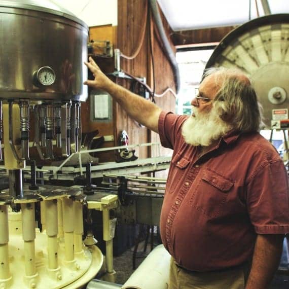 a bearded man explaining wine-making equipment