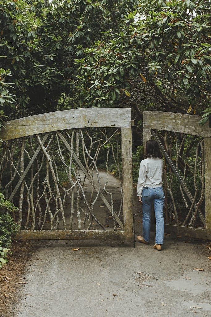 a woman walking through a wooden gate