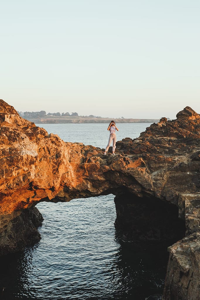 woman standing on a natural rock bridge over the ocean