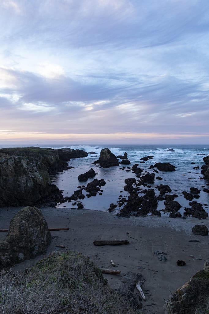 a beach with rocky cliffs at dusk